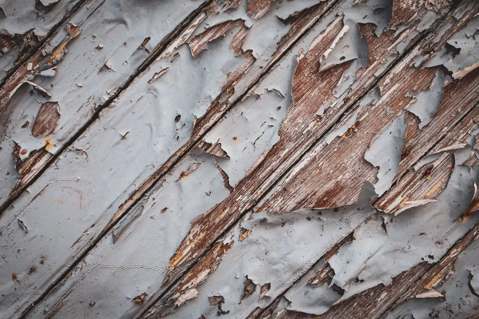 Peinture écaillée sur des planches de bois abîmées par les intempéries