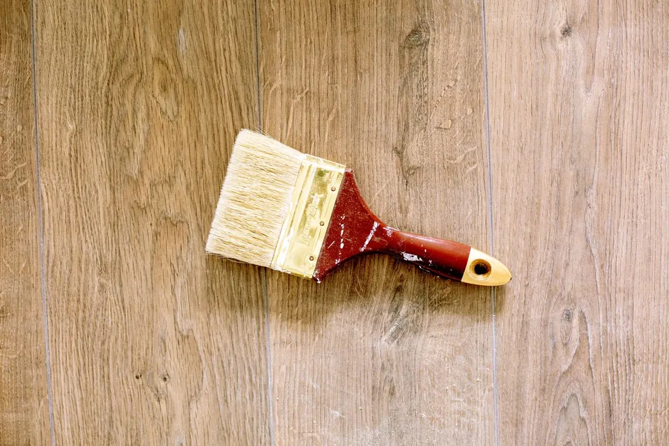 Pinceau posé sur un parquet clair